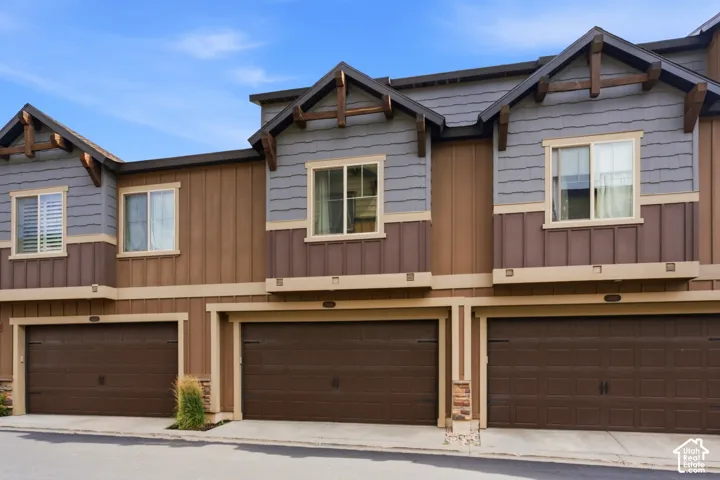Multi-level townhome exterior featuring shingle siding, vertical board siding, and decorative wood gables