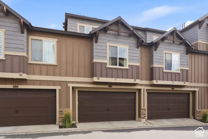 Multi-level facade with mixed material siding, individual garage doors, and decorative gable accents