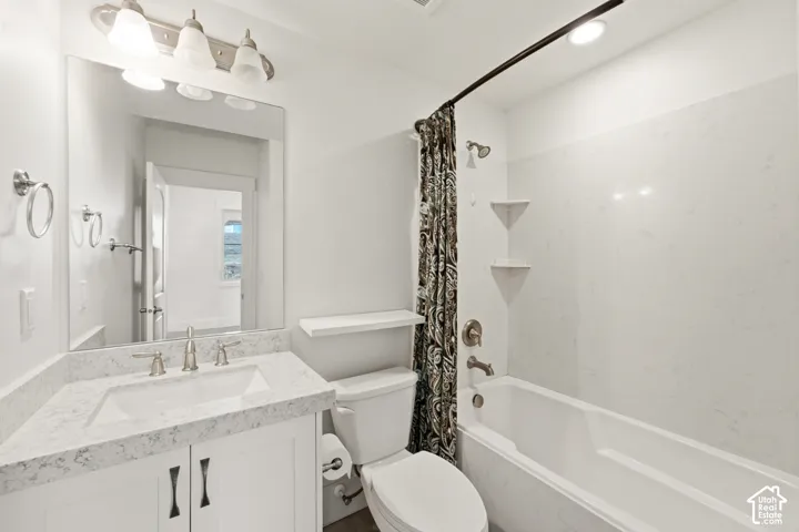 Bathroom featuring a white vanity with brushed nickel hardware, an undermount sink, and a stone-finish countertop