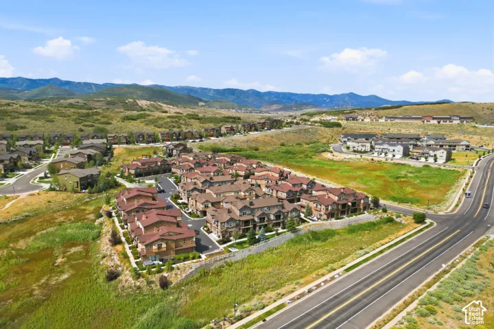 Residential community with varied architectural styles, paved roadways, and surrounding natural landscapes, set against a backdrop of distant mountains