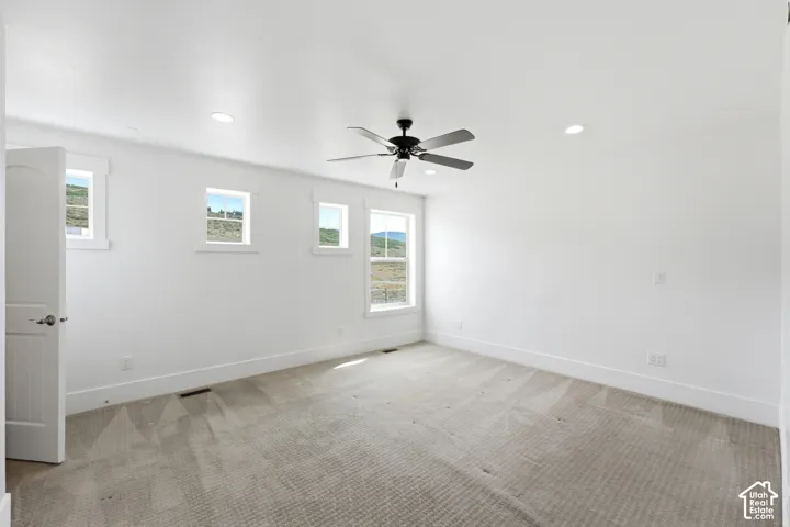 Recessed lighting, ceiling fan, white walls, multiple windows, and light-toned carpet
