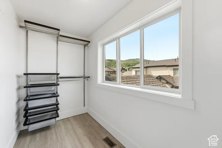 Adjustable closet shelving system, integrated wire drawers, large window, white trim, and wood-finish flooring