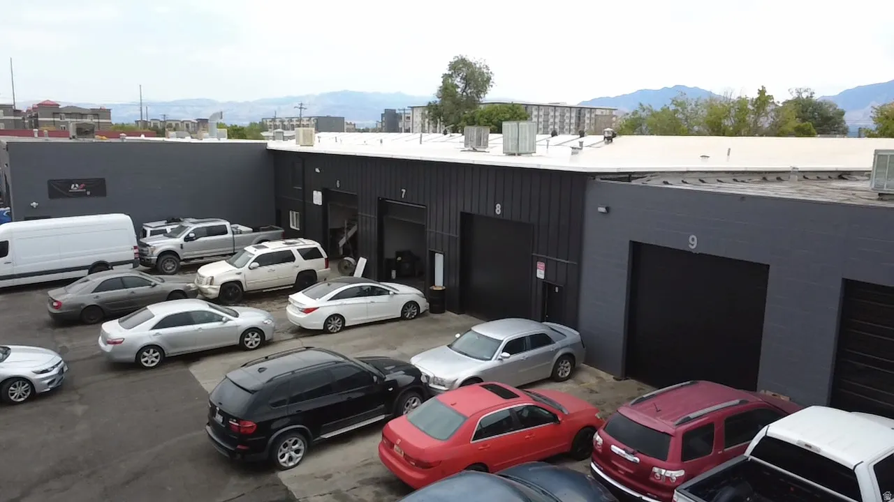 Industrial facility with multiple dark-painted roll-up doors, a flat roof, and a paved lot
