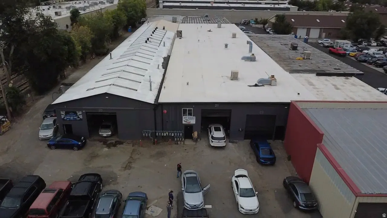 Expansive commercial building featuring multiple garage bays, a large flat roof, and an additional sloped roof section