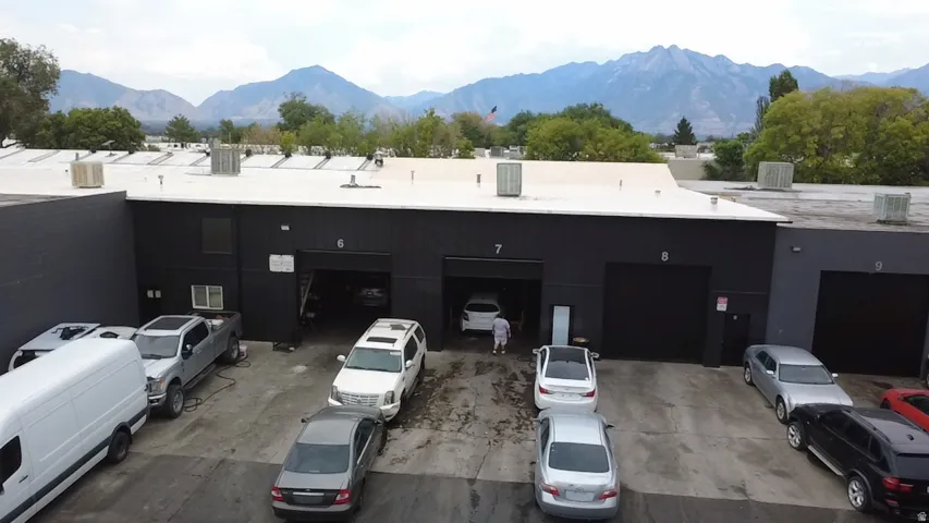Industrial building with multiple bay doors, a paved lot, and a mountain backdrop