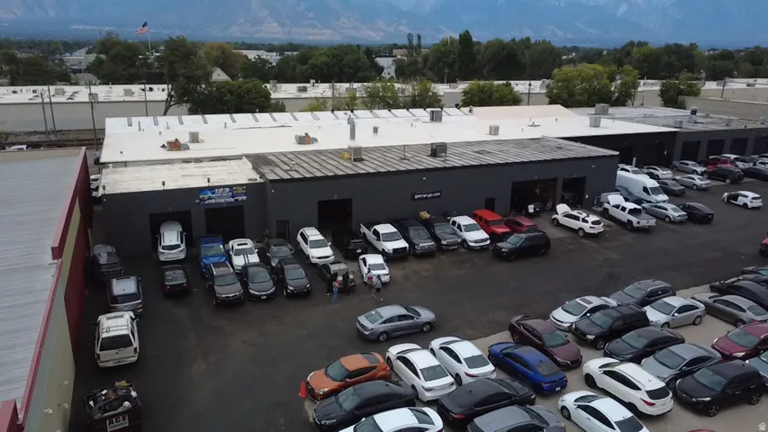 Commercial building featuring multiple garage bays, an expansive paved parking area, and a flat roof