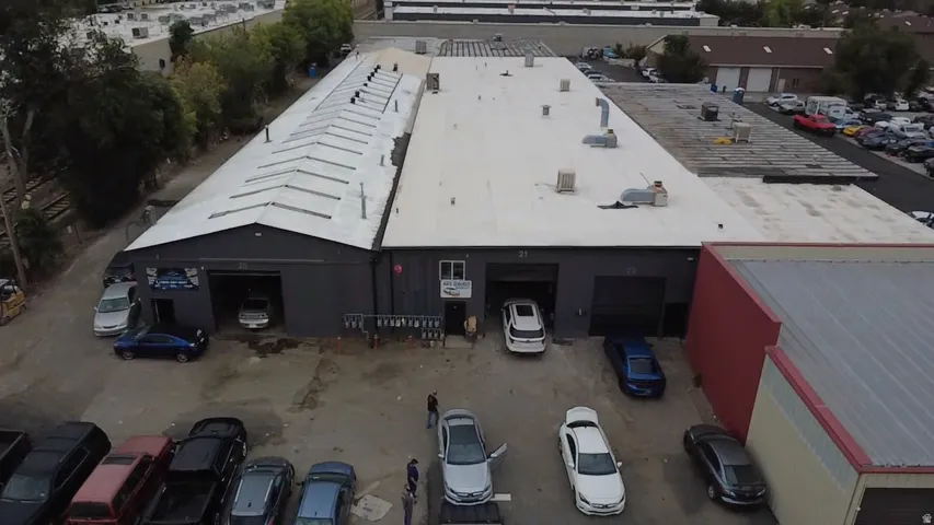 Expansive commercial building featuring multiple garage bays, a large flat roof, and an additional sloped roof section