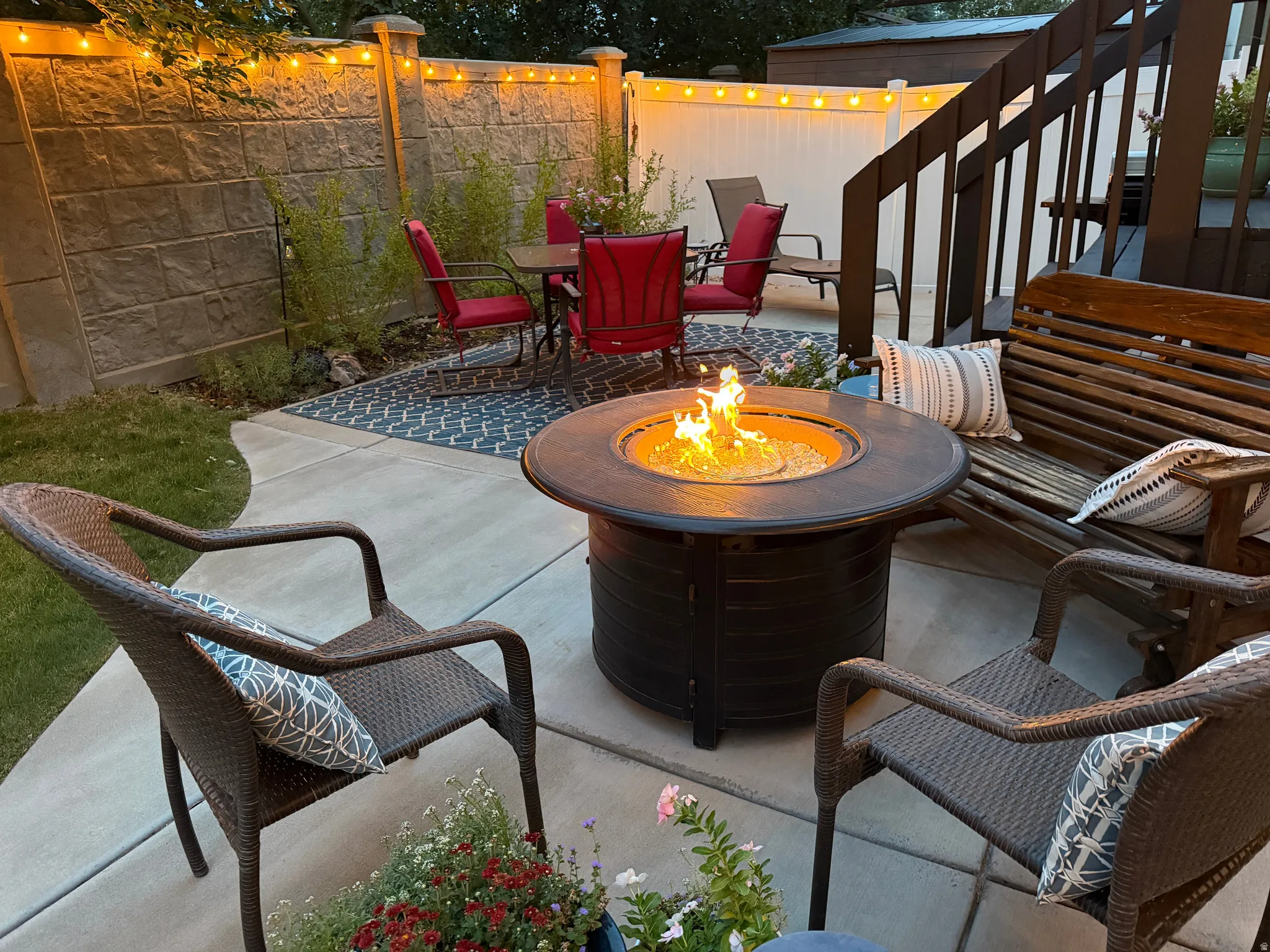 Paved patio area featuring a built-in fire pit, privacy fencing, and wood-finish stairs