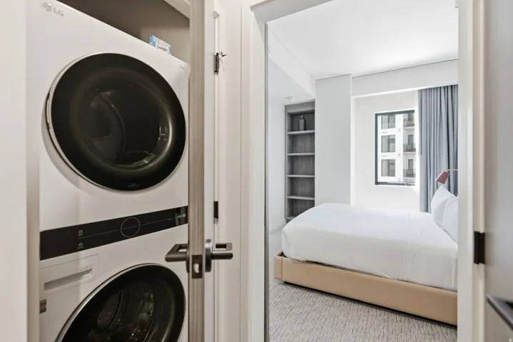 Stackable washer and dryer unit, built-in shelving, and a window with urban architecture