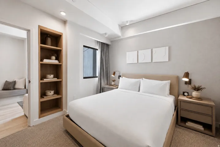 Built-in wood-finish shelving, recessed ceiling lighting, a window with curtain treatments, and built-in wall sconces