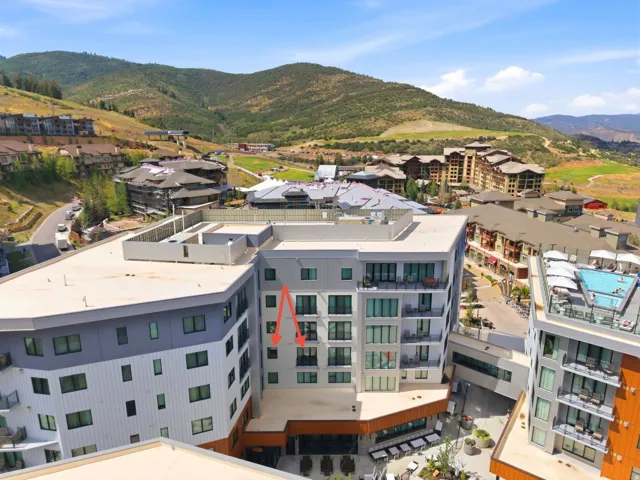 Multi-story building featuring balconies, flat roof, and a visible rooftop pool on an adjacent structure