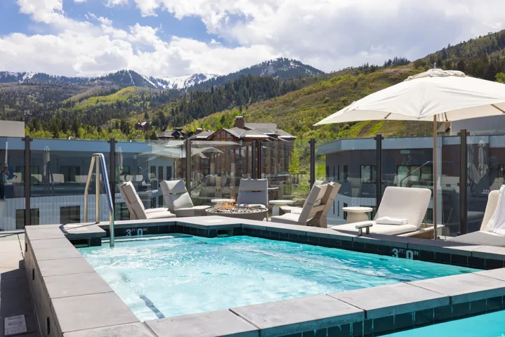 Rooftop terrace featuring a rectangular spa, glass panel railing, and integrated fire pit