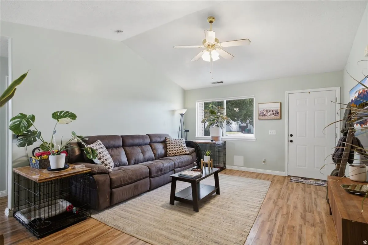 Vaulted ceiling, wood-finish flooring, ceiling fan, and white trim