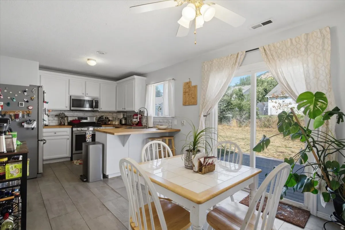 White cabinetry with wood-finish countertops, stainless steel appliances, and a tile backsplash