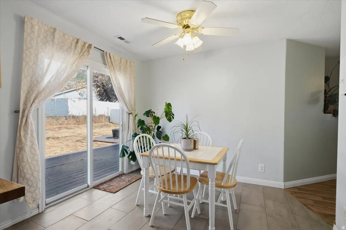Sliding glass door, wood-finish flooring, ceiling fan with light fixture, and light-toned walls