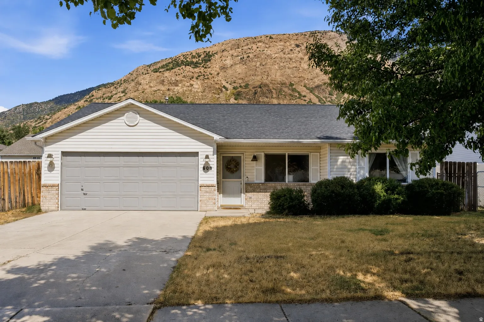 Single-story residence featuring a two-car garage, white siding, and a dark shingle roof