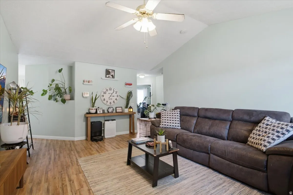 Vaulted ceiling with a ceiling fan, wood-finish flooring, and a console table