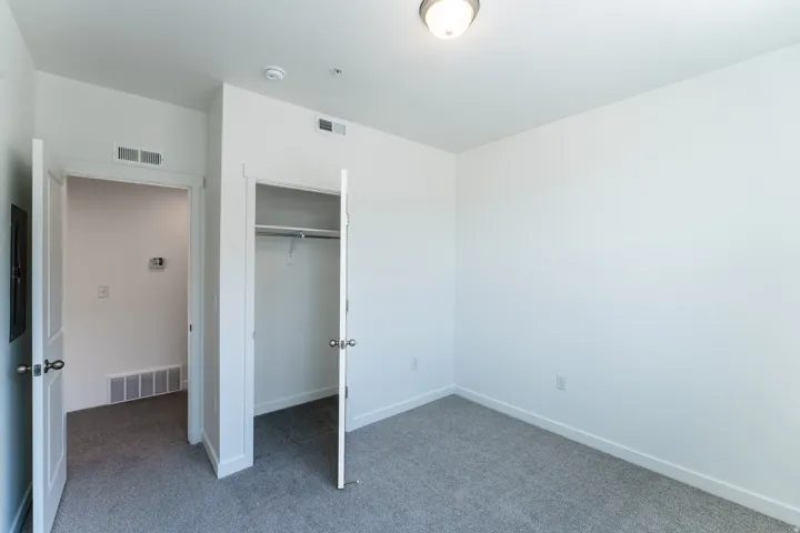 Carpeted bedroom with a built-in closet featuring a clothes rod and wire shelf