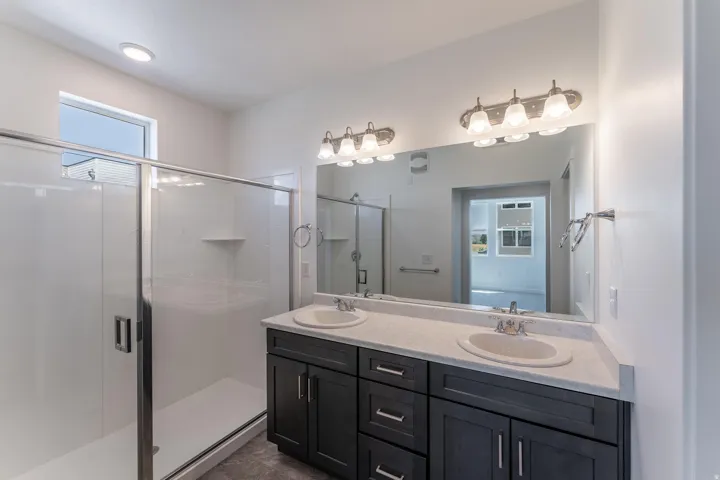 Bathroom featuring a double vanity with dark wood-finish cabinetry, light-colored countertops, and dual undermount sinks