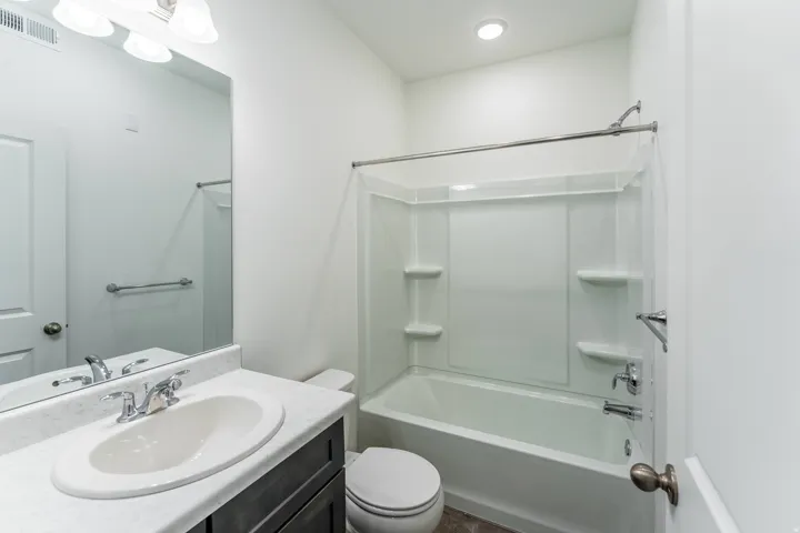 Bathroom featuring a vanity with a white oval sink, chrome faucet, and dark wood-finish cabinetry