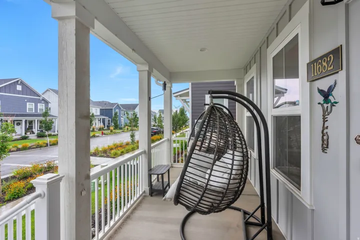 Covered porch with concrete flooring, white balustrade railing, and vertical siding