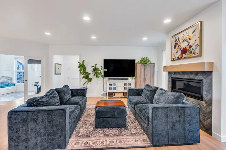 Recessed lighting illuminates the living area with wood-finish flooring