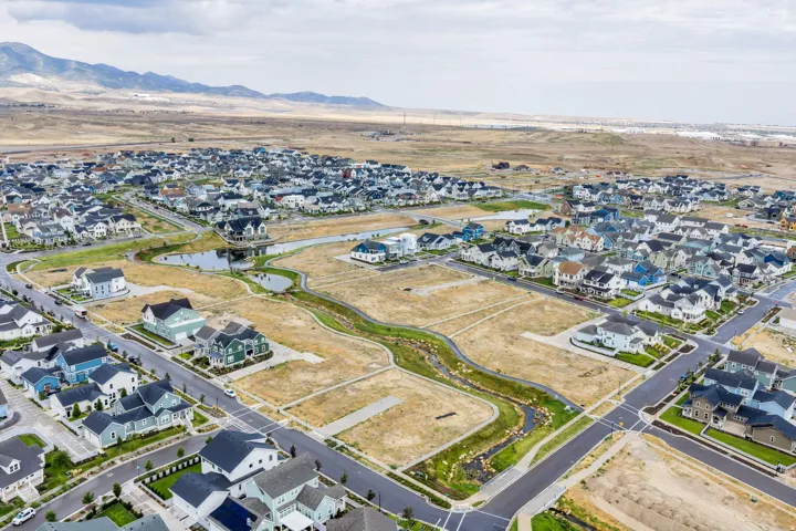 Expansive residential development featuring numerous single-family homes, paved streets, and a developing greenway with water features
