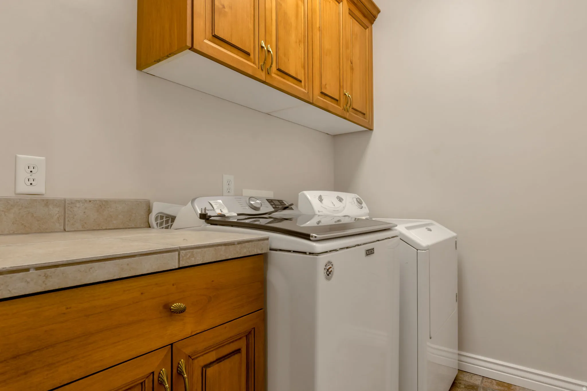 Light wood-finish cabinetry, tile countertop, and light wall paint