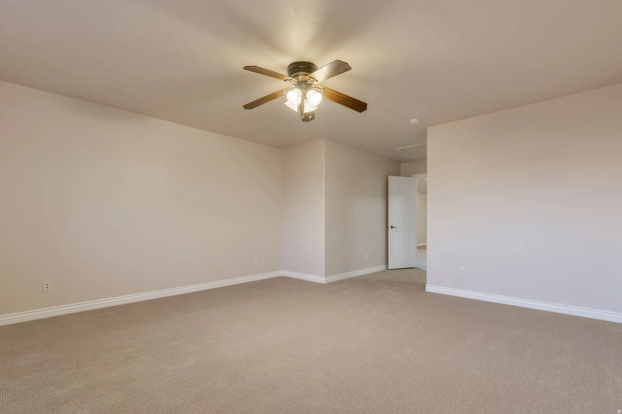 Neutral tone wall paint, light neutral tone carpet flooring, ceiling fan with light fixture, white trim, and white door