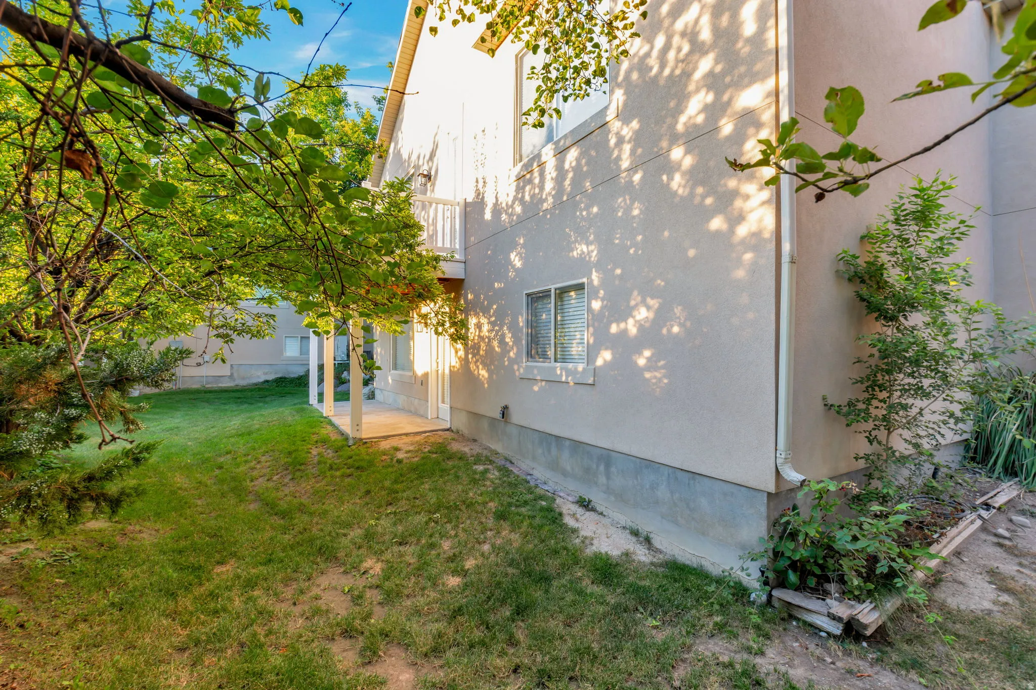 Stucco exterior with a ground-level concrete patio and an upper-level balcony featuring white railings