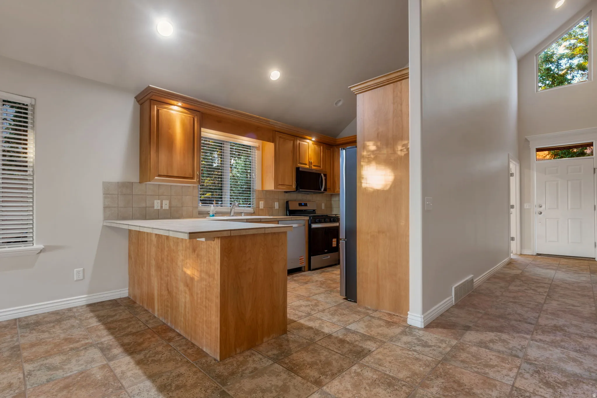Kitchen with wood cabinetry, stainless steel appliances, and a tiled backsplash