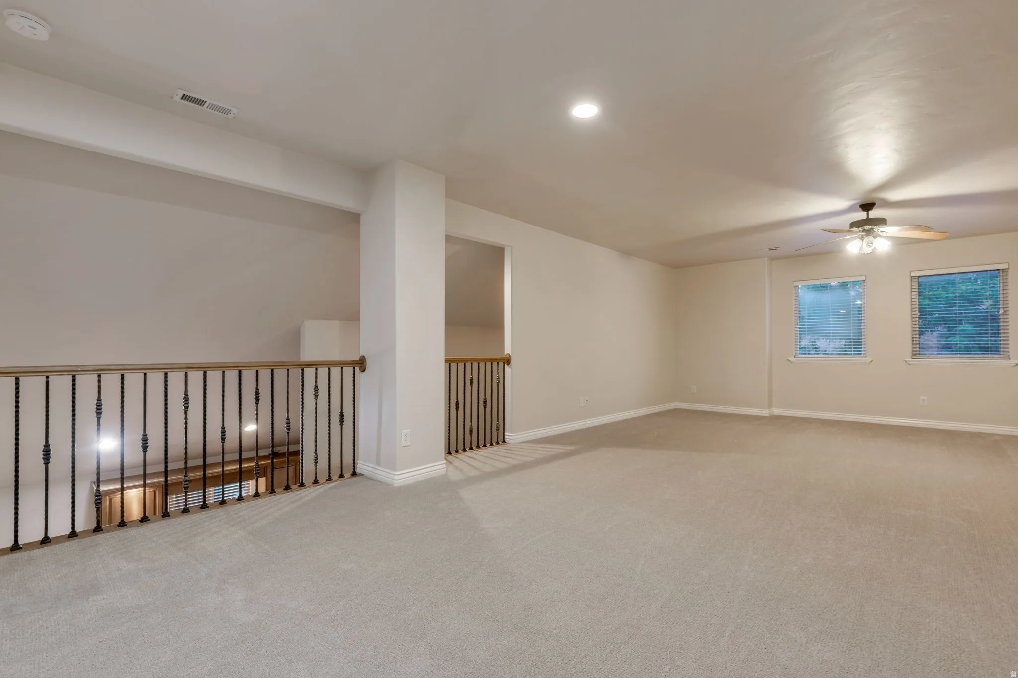 Spacious carpeted room featuring recessed lighting, a ceiling fan, and two windows