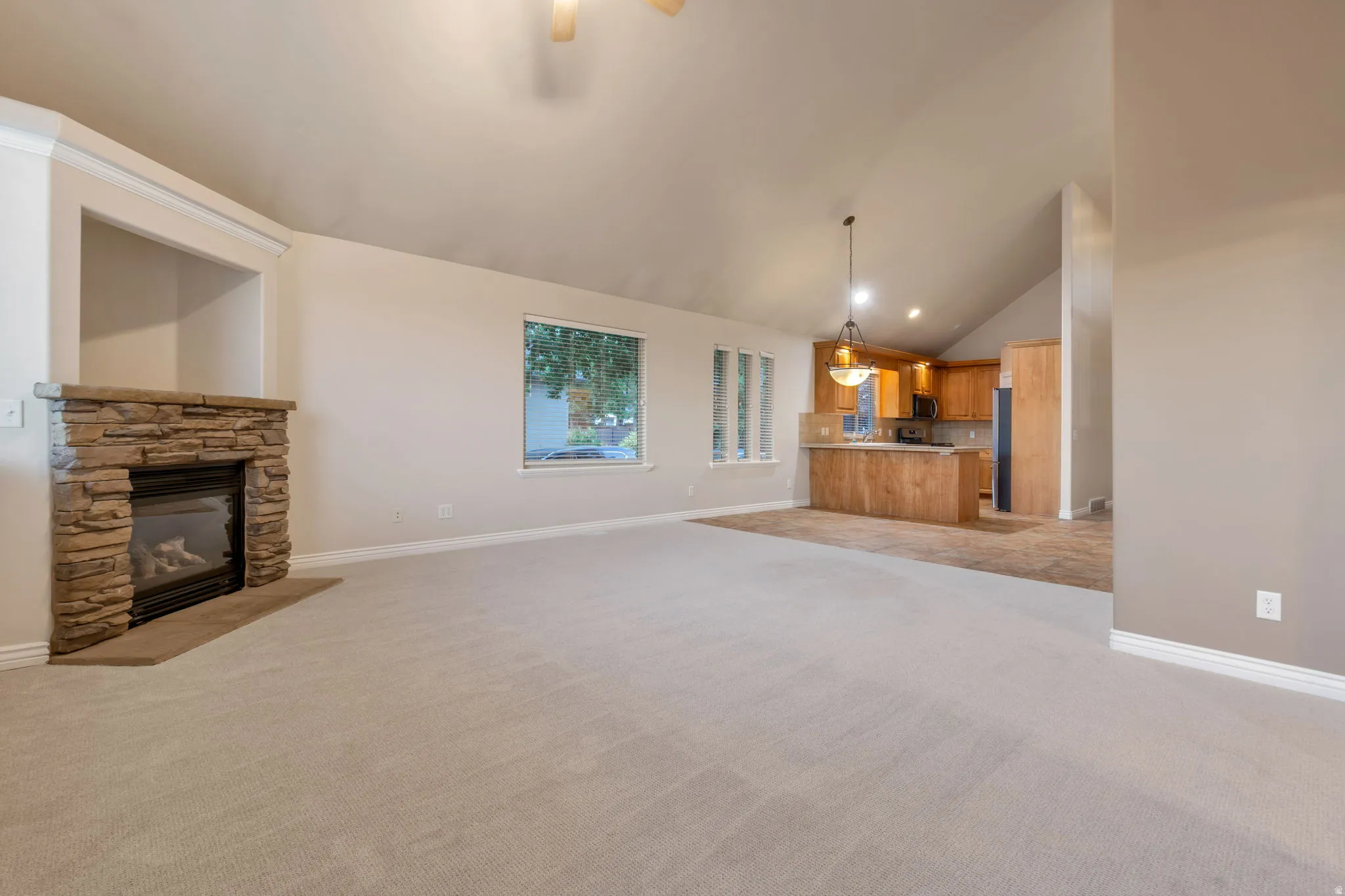 Living area featuring a stone-clad fireplace with a built-in niche, vaulted ceiling, and recessed lighting