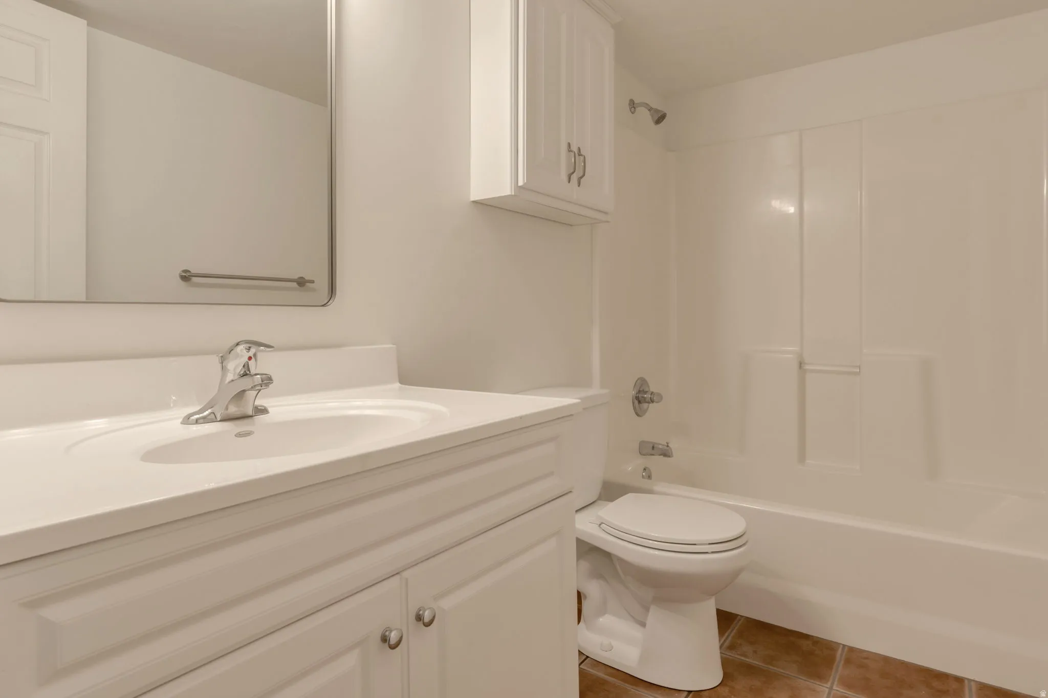 White vanity with integrated sink, chrome faucet, white wall-mounted cabinet, and an integrated bathtub and shower unit