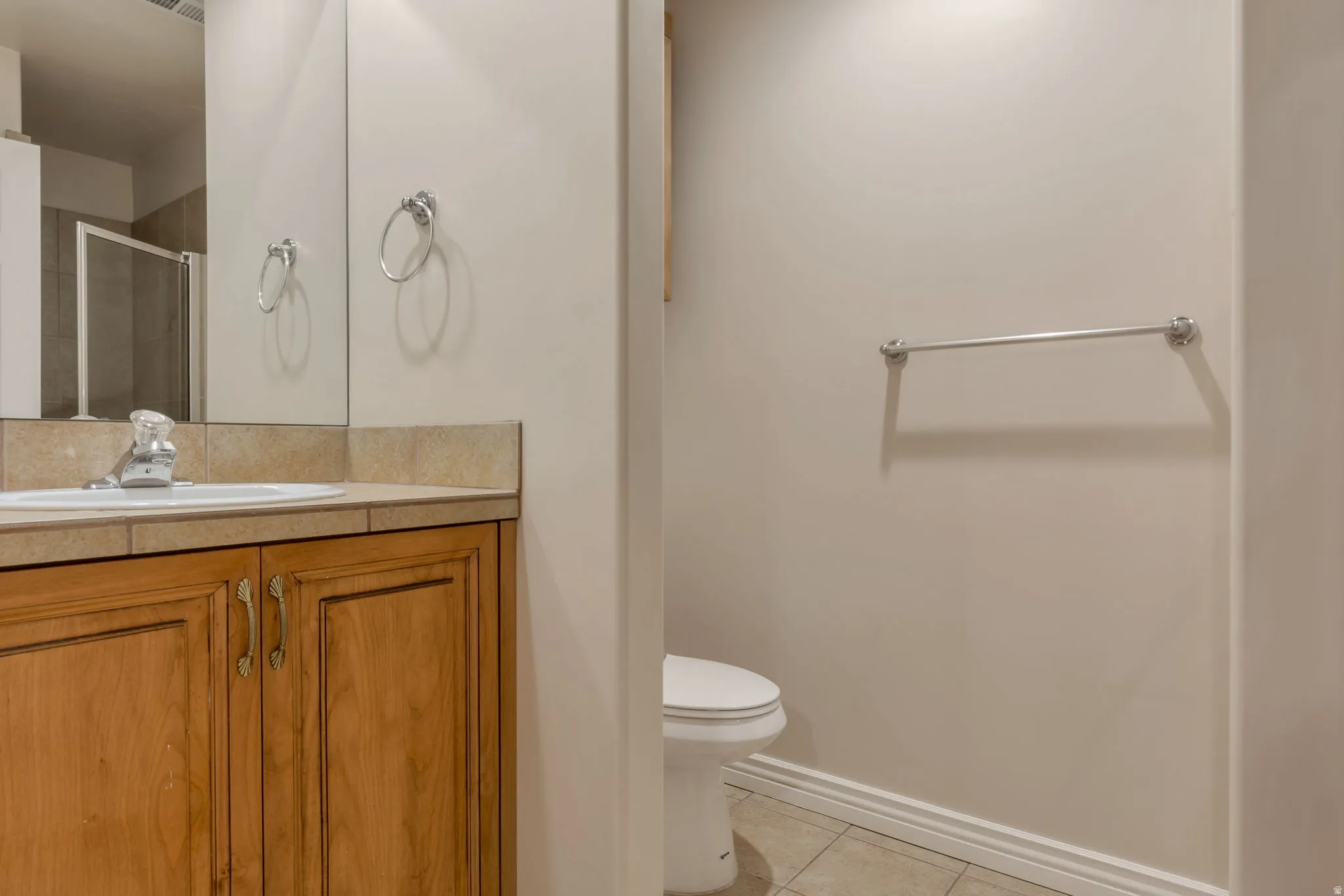 Wood-finish vanity with an integrated sink, tile countertop, and polished chrome fixtures