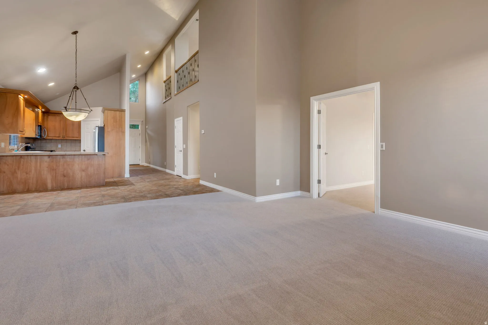 Vaulted ceilings, a second-story balcony with decorative railing, and recessed lighting