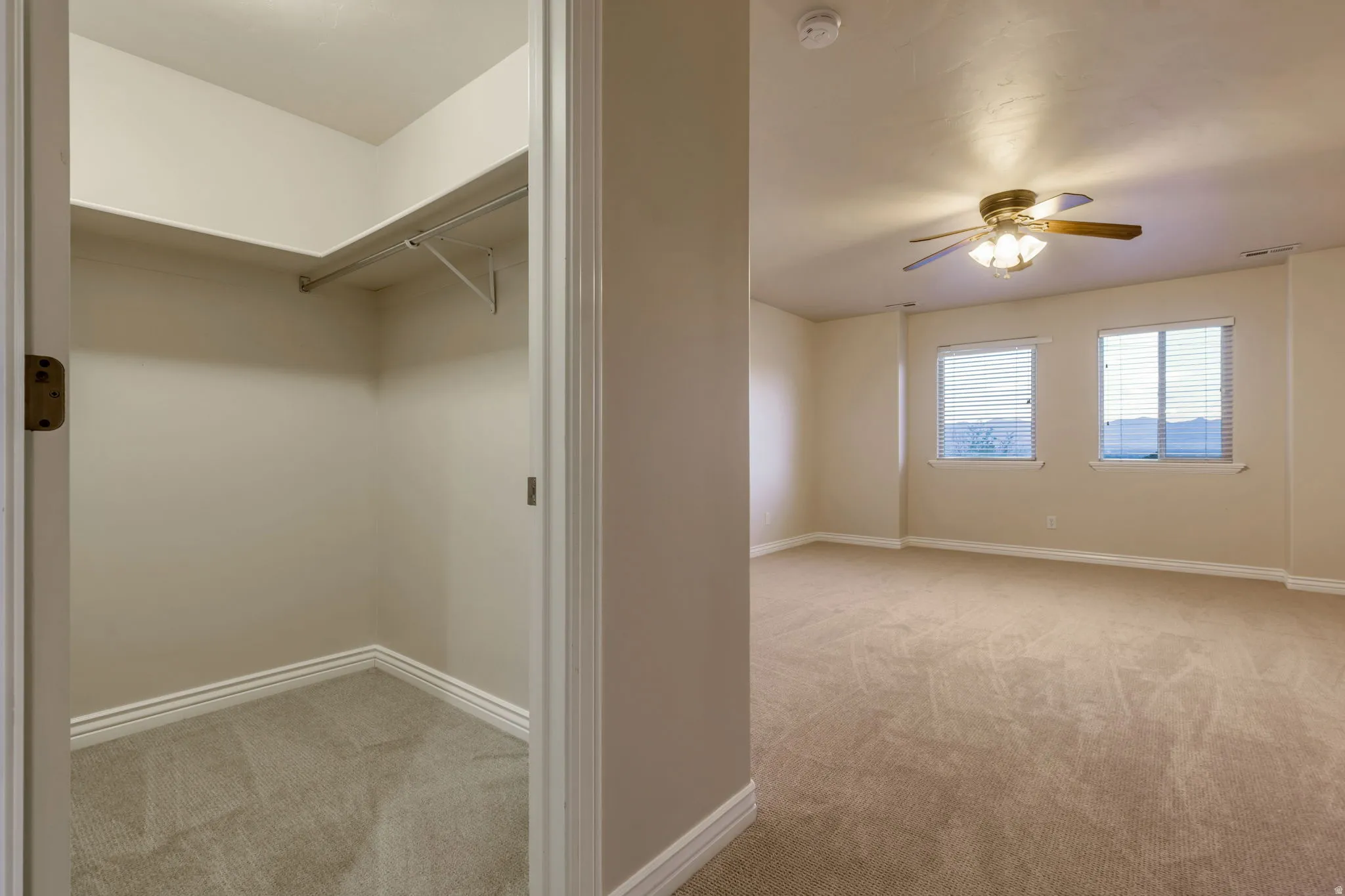 Spacious room with carpet flooring, twin windows, and a ceiling fan