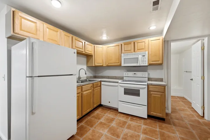 Kitchen featuring wood cabinetry, white appliances, integrated sink, and recessed lighting