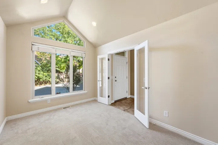 Vaulted ceiling, recessed lighting, expansive window arrangement, and French doors