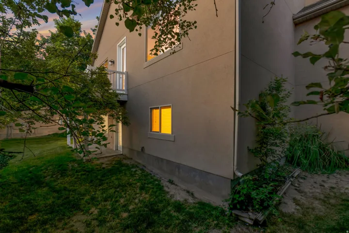 Stucco exterior with multiple windows, an upper-level balcony, and a lower-level patio door