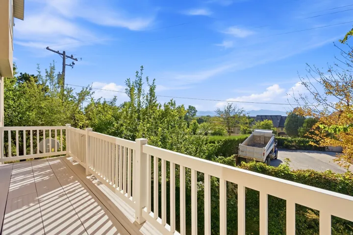 Outdoor balcony with white railing, composite decking, and distant mountain scenery