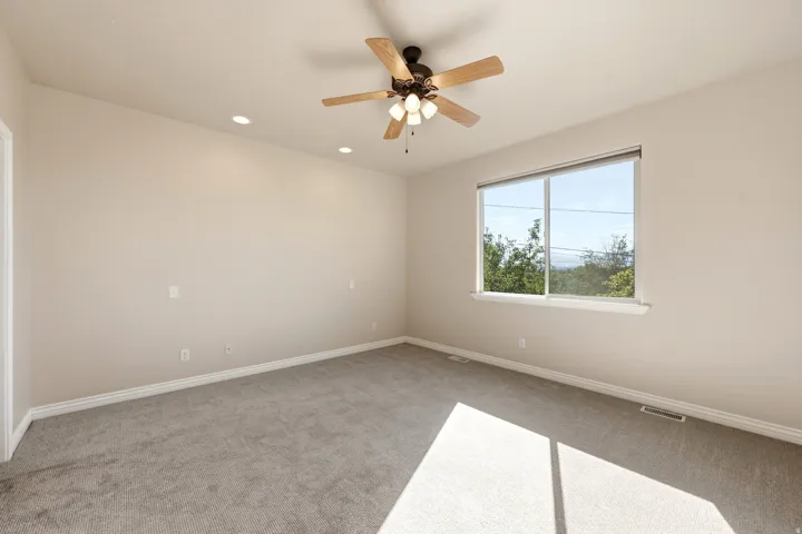 Spacious room featuring neutral carpeting, recessed lighting, and a ceiling fan