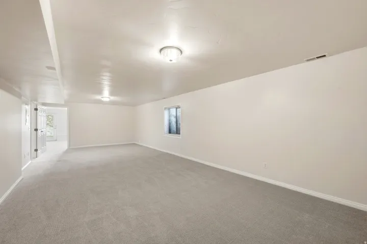 Spacious room featuring light gray carpeting, white walls, and recessed lighting