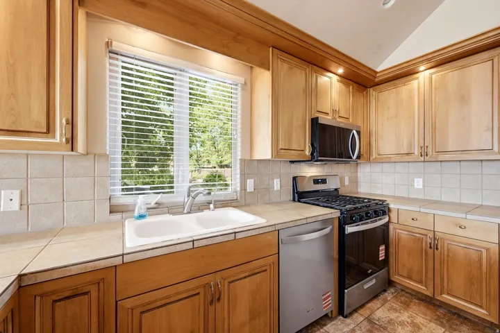 Kitchen with wood-finish cabinetry, tile countertops, and a dual basin sink