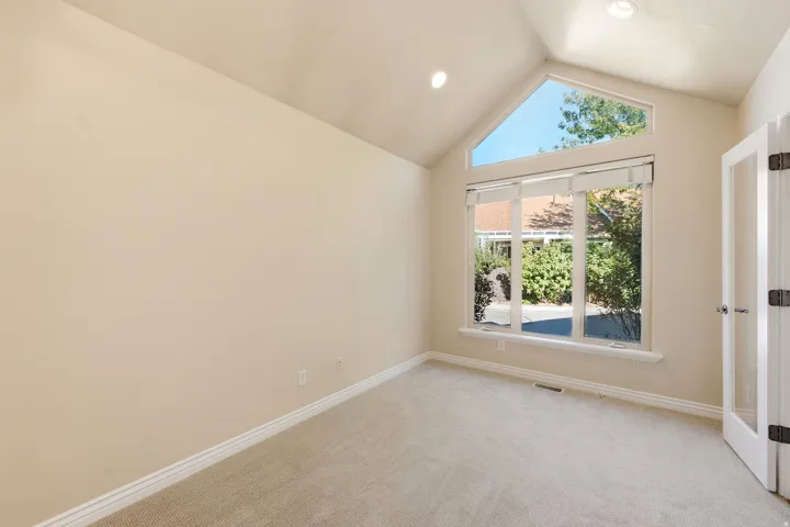 Soaring vaulted ceilings with recessed lighting, large windows with upper transom, and a glass-paneled interior door