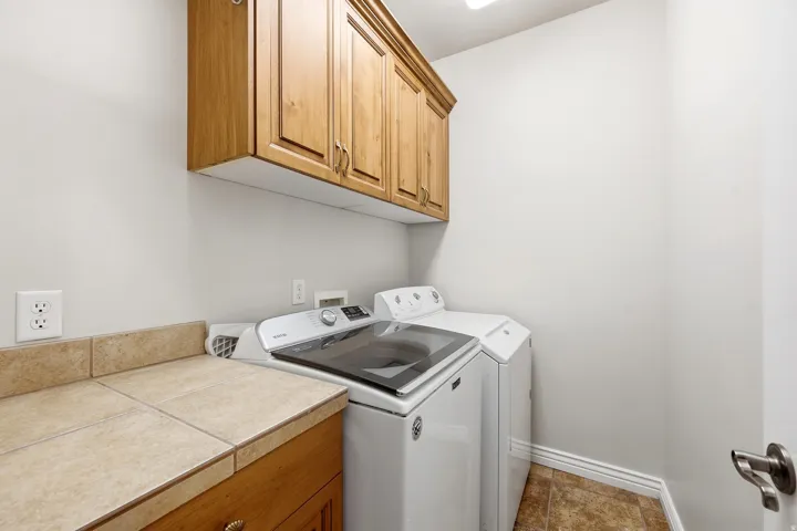 Built-in wood cabinetry, tiled countertop, under-counter storage, tiled flooring, and neutral wall tones