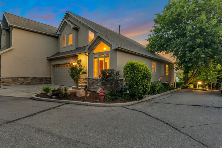 Stucco exterior with stone accenting, an attached garage, and a peaked roofline