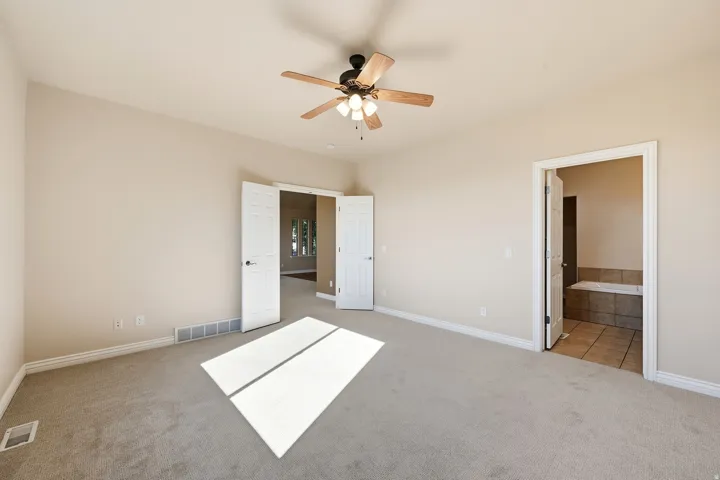 Carpeted room with a ceiling fan, vaulted ceiling, and dual paneled doors