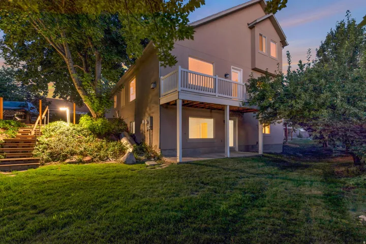 Two-story exterior with a second-level balcony, ground-level patio, and exterior lighting