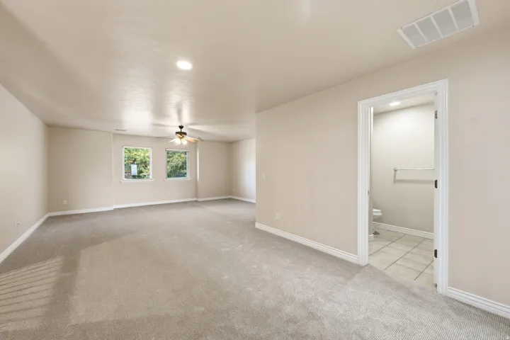Expansive carpeted room featuring multiple windows, a ceiling fan, and recessed lighting